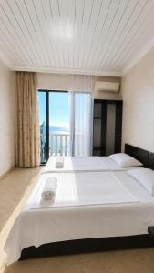 a large white bed in a room with a large window at У Царицы in Kobuleti