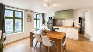 a kitchen with a wooden table and white chairs at Le Clos Delobel in Tourcoing