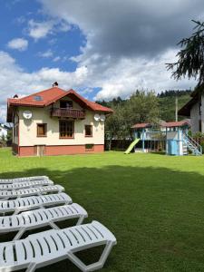 a group of white chairs on a lawn with a playground at КАТАМАН ХАУС - басейн з підігрівом in Slavske