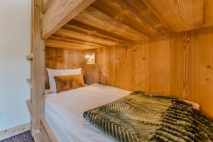 a bed in a room with wooden walls at Le Bellacha in La Léchère