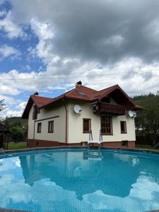 a house with a swimming pool in front of it at КАТАМАН ХАУС - басейн з підігрівом in Slavske
