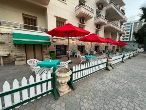 a row of tables and chairs with red umbrellas at Revira Palace - Marsa Matrouh in Marsa Matruh