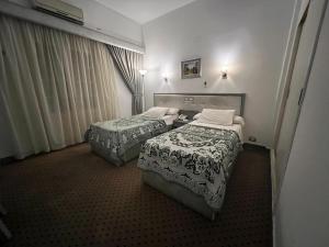 a hotel room with two beds and curtains at Revira Palace - Marsa Matrouh in Marsa Matruh