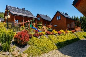 a house with a garden in front of it at Osada Zawóz domki z balią jacuzzi i sauną nad Jeziorem Solińskim in Zawóz