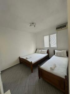 two beds in a room with white walls and wood floors at Apartmani Glory Sutomore in Sutomore +6 photos