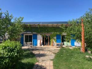 a blue and white house with a patio at L'Abeille-Vie in Tréziers