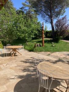 a patio with tables and chairs and a table and a tree at L'Abeille-Vie in Tréziers +9 photos