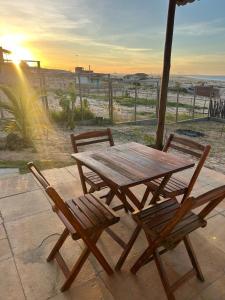 a wooden table and chairs with the ocean in the background at Villa Maze Suites - Canoa Quebrada in Aracati +1 photo