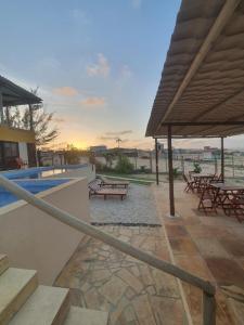a patio with a pool and picnic tables and an umbrella at Villa Maze Suites - Canoa Quebrada in Aracati