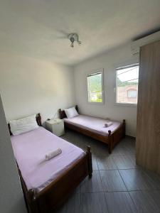 a bedroom with two beds and two windows at Apartmani Glory Sutomore in Sutomore