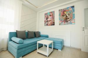 a living room with a blue couch and two paintings at Apartmani SLEEP&JOY in Zlatibor