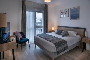 a bedroom with a bed and a chair and a window at DOMITYS - Les Canotiers in Argenteuil +7 photos
