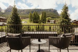 a balcony with chairs and a table and mountains at Hotel La Majun in La Villa