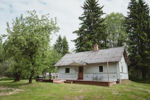 a white house with a porch in a field at Peaceful Forest Cabin in Nature in Paluküla