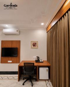 a room with a desk and a chair and a television at Hotel gardenia inn in Gwalior +3 photos