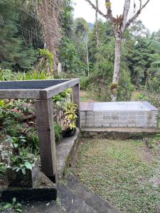 a stone bench in a garden with trees in the background at Espaço Colibri in Teresópolis