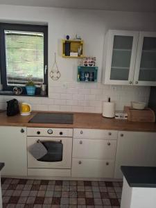 a kitchen with white cabinets and a stove top oven at Őrségi Csónakház in Hegyhátszentjakab +4 photos