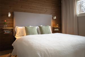 a bedroom with a white bed with a wooden wall at Nordic Lapland Frevisören in Båtskärsnäs