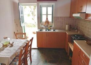 a kitchen with a table and a sink and a window at Lefkiani House in Katapola