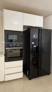 a black refrigerator in a kitchen with white cabinets at Hotel Le Bleu Marine in Saintes-Maries-de-la-Mer