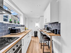 a kitchen with white cabinets and a counter with stools at LetSavvy Contractor Accommodation Hartlepool in Hartlepool
