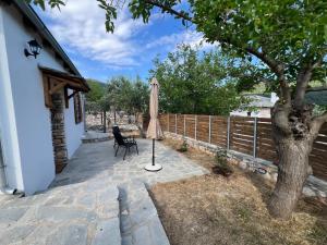 a patio with an umbrella and a chair next to a tree at Linos Old Barn in Theológos