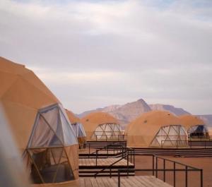 a row of domed tents with mountains in the background at WADI RUM ROTANA BUBBLE lUXURY in Wadi Rum