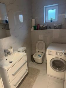 a white bathroom with a toilet and a sink at Apartman Provo in Široki Brijeg