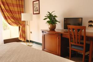 a hotel room with a desk with a television and a chair at Minerva Resort Hotel in Paestum