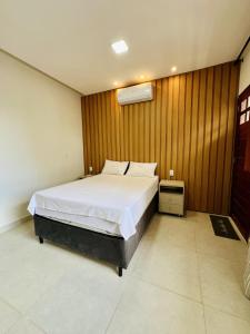 a bedroom with a bed and a wooden wall at Flat completo em condomínio in Camocim +11 photos