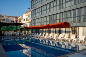 a pool with chairs and an umbrella next to a building at Velaris Boutıque Hotel in Belek