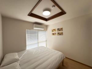 a bedroom with a white bed and a window at 羽憩館 Hakeikan KIX in Izumi-Sano