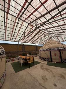 a patio with a table and chairs under a tent at Son kol Keng suu guesthouse in Keng-Suu