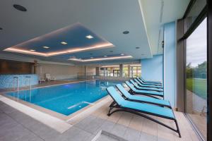 a pool with a row of chairs in a building at Second Home Luxury Apartman in Siófok