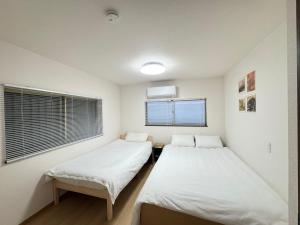 two beds in a room with a window at 羽憩館 Hakeikan KIX in Izumi-Sano