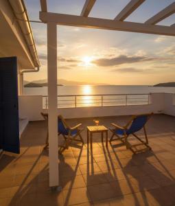 a balcony with a table and chairs and a sunset at Gaia Skiathos Apartments in Achladies