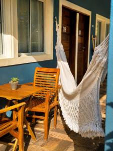 a hammock on a porch with a table and chairs at Pousada Alto da Vila Noronha by Alto da Ilha in Fernando de Noronha