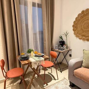 a living room with a table with orange chairs and a couch at Bali island Home2 in Al Khobar