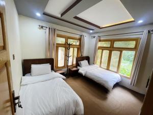 two beds in a room with two windows at Alpine Resort Khaplu in Khaplu +40 photos