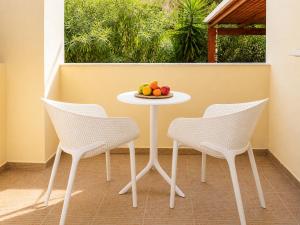 a table with two chairs and a bowl of fruit on it at Astir Studios in Stalís