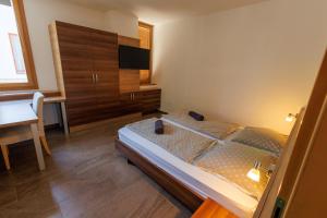 a bedroom with a bed and a dresser and a television at Jacht Apartmanok in Balatonfüred
