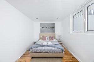 a white bedroom with a bed and a window at A Lodge in Blue in Aveiro