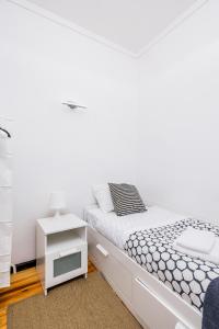 a white bedroom with a bed and a night stand at A Lodge in Blue in Aveiro