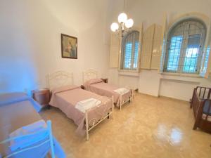 a bedroom with two beds and a chandelier and windows at Salento mare in Casalabate