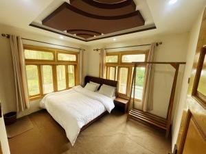 a bedroom with a bed with white sheets and windows at Alpine Resort Khaplu in Khaplu