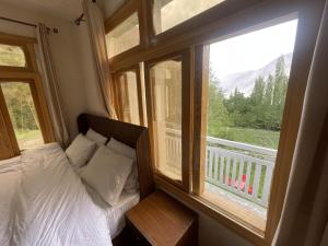 a bedroom with a bed and a large window at Alpine Resort Khaplu in Khaplu