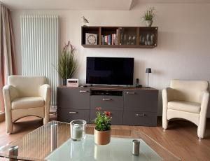 a living room with a tv and two chairs at Ferienwohnung De Kraan in Dorum-Neufeld