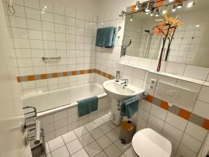 a bathroom with a sink and a toilet and a tub at Ferienwohnung De Kraan in Dorum-Neufeld +3 photos