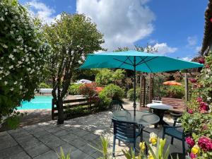 a table with a blue umbrella next to a pool at Maison d'Hôtes L'Escale Du Loup Blanc in Maringes