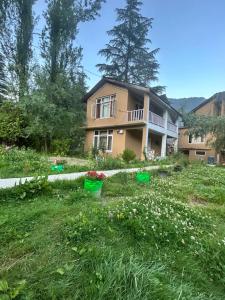 a house with a yard with flowers in the grass at Hotel Devidyar in Manāli
